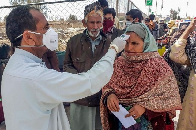 a health official checks the body temperature of a pilgrim returning from iran via the pakistan iran border town of taftan on feb 29 2020 photo afp