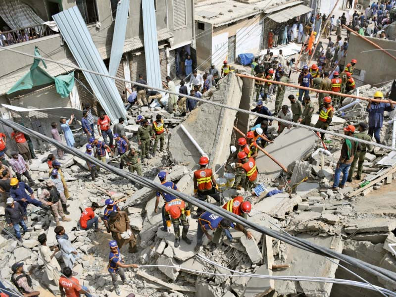 rescue workers search for survivors in the debris of an illegally constructed structure in shah faisal colony photo online