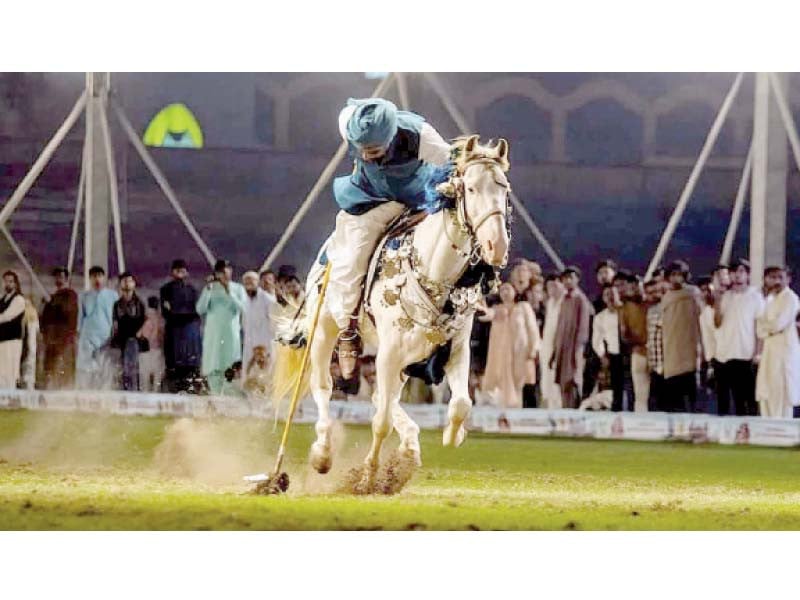 a horseman successfully spears a tent peg during the pha tent pegging contest in lahore photo nni