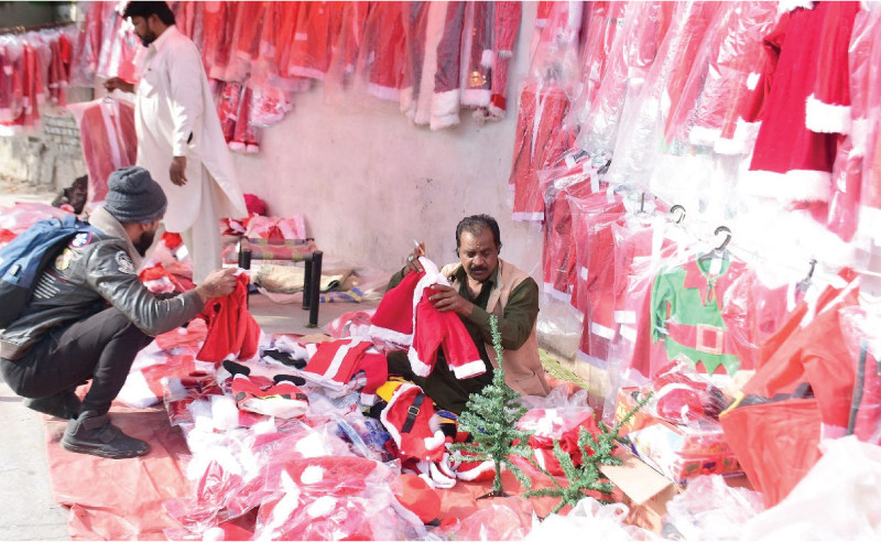 members of the christian community take interest in santa claus costumes up for sale at a roadside stall in sector g 7 of the federal capital photo online