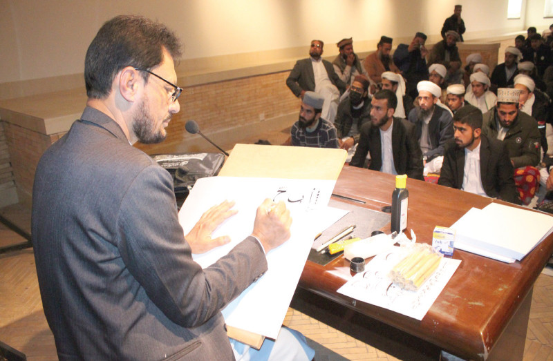 an instructor gives calligraphy lessons to students of a seminary in a workshop held by the pakistan national council of the arts photo express