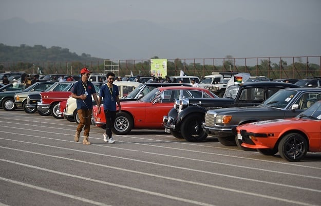 Participants walk past cars at the end of Motor Rally in Islamabad. PHOTO: AFP