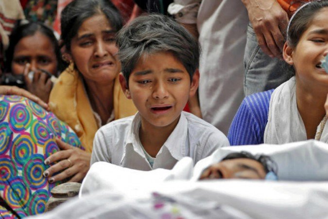 people mourn next to the body of a riot victim in new delhi on february 27 2020 photo reuters