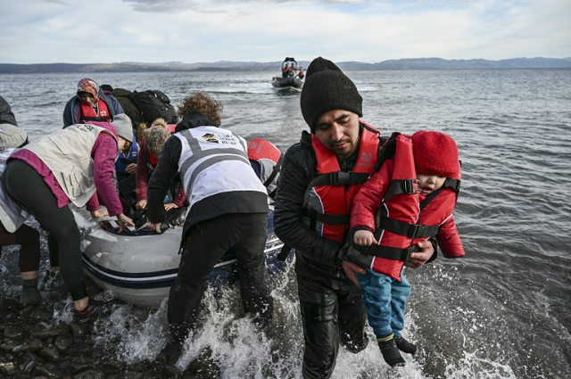 ngo members help refugees to disembark from a dinghy as it lands ashore the greek island of lesbos photo afp