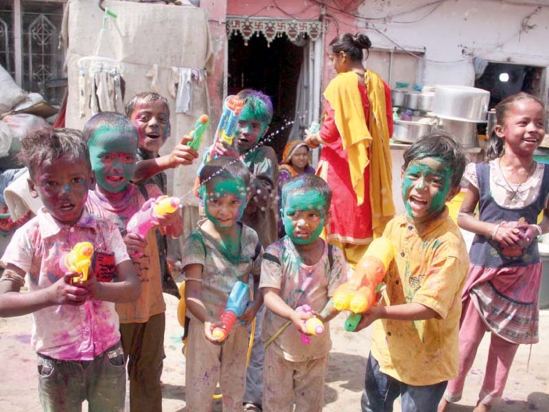 children holding water guns are covered in coloured powder as they celebrate the festival of holi at the swaminarayan temple in karachi photo online