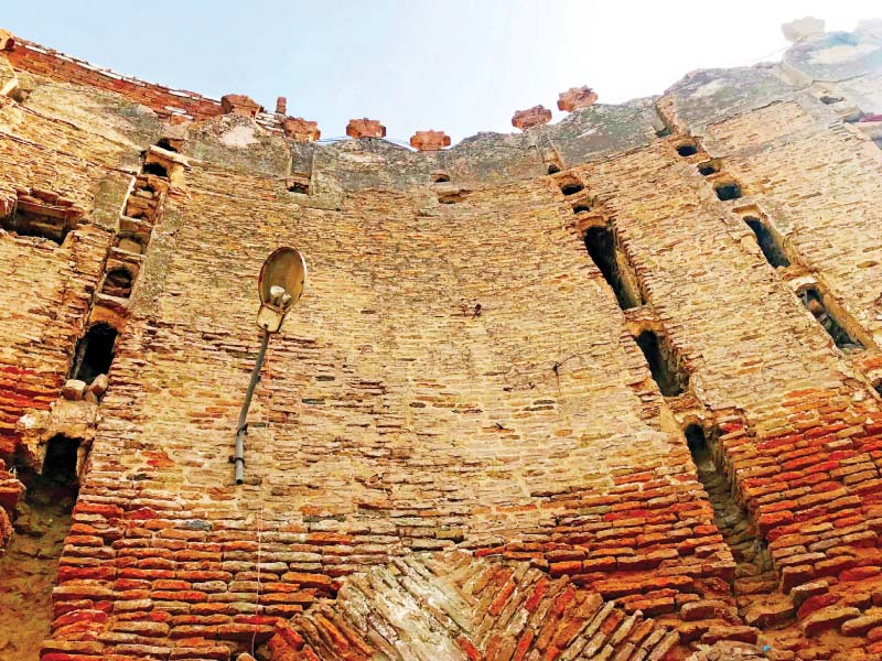 a street light hangs crookedly off the imposing walls of pakka qila residents have set up shelter and small business enterprises within the walls leading to the further deterioration of the once glorious fort photos express