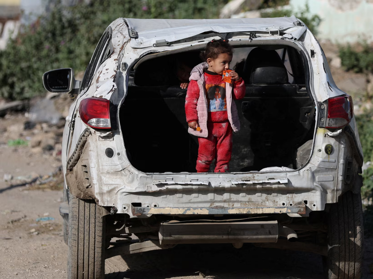 A Palestinian child stands in the trunk of a damaged car near a cemetery during Eid al-Fitr, in Gaza City, March 20, 2026. REUTERS