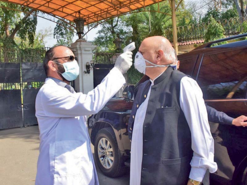 a doctor checks governor sarwar s body temperature at the main gate of the governor s house photo express