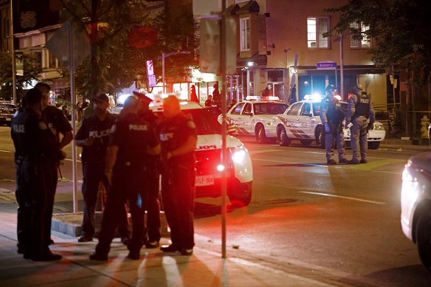 Toronto Police officers walk the scene at Danforth St. at the scene of a shooting in Toronto. PHOTO:AFP