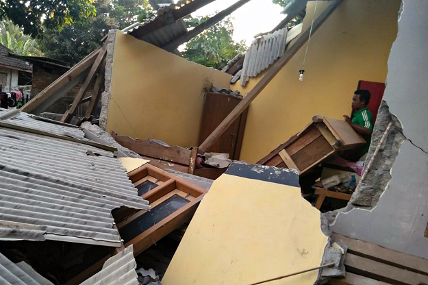 An Indonesian man standing among the collapsed ruins of a house following an earthquake in Lombok. PHOTO:AFP