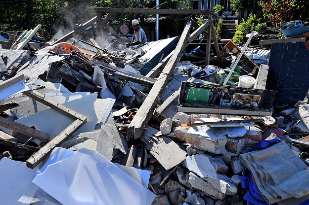 A man salvages valuable items from the rubble of damaged houses in Menggala. PHOTO:AFP