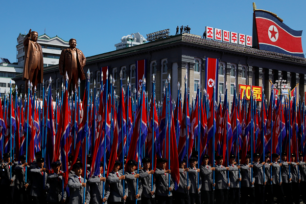 People carry flags in front of statues of North Korea founder Kim Il Sung and late leader Kim Jong Il. PHOTO:REUTERS