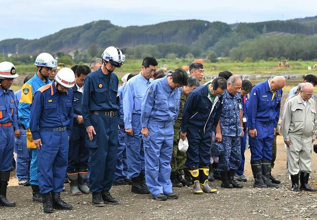 Japanese Prime Minister Shinzo Abe (C) pays tribute to the victims of the devastated city of Atsuma. PHOTO:AFP