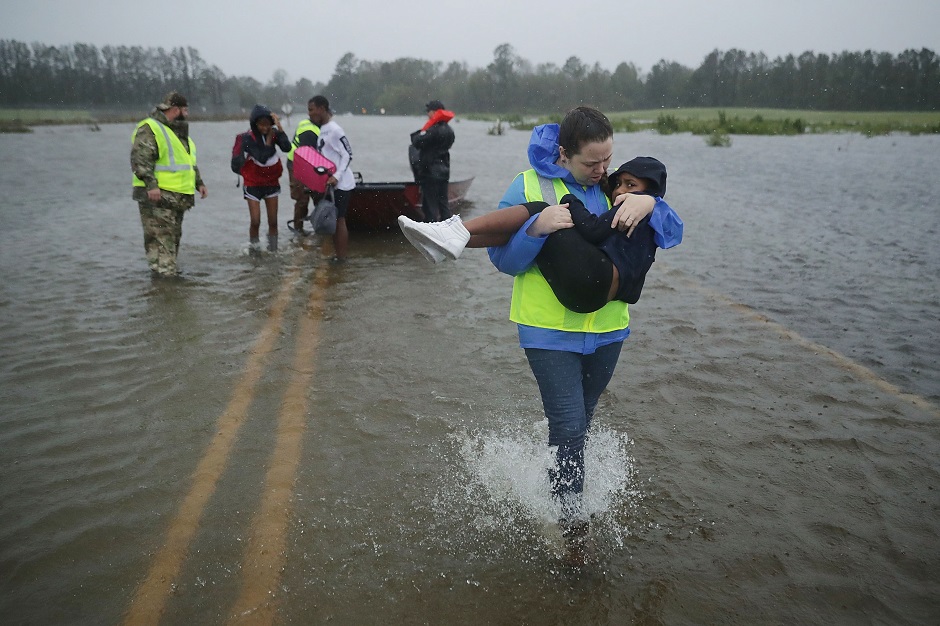 Rescue worker carries a child from rescue boat to shelter PHOTO: AFP