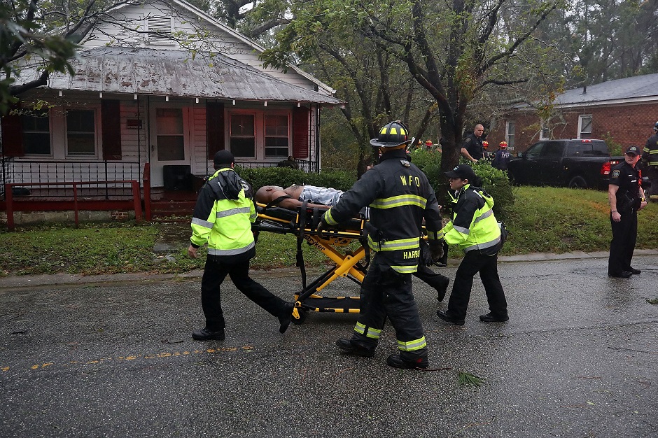 Rescue personnel remove a man from a home that a large tree fell on after Hurricane Florence hit the area PHOTO: AFP