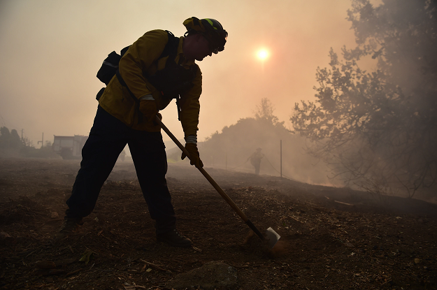 Local residents watch as firefighters control a flare up from the Woolsey Fire. PHOTO: AFP