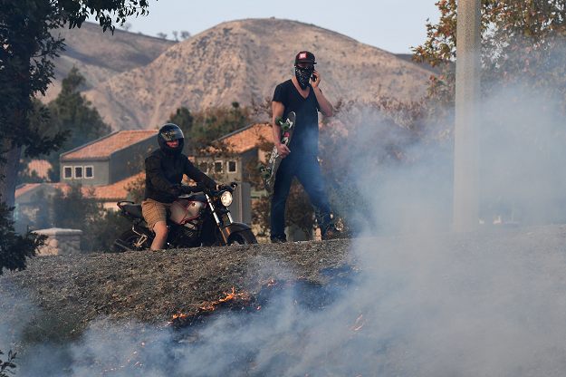 Local residents watch as firefighters control a flare up from the Woolsey Fire. PHOTO: AFP