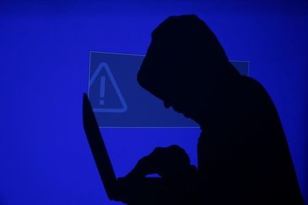 a hooded man holds a laptop computer as blue screen with an exclamation mark is projected on him in this illustration picture photo reuters