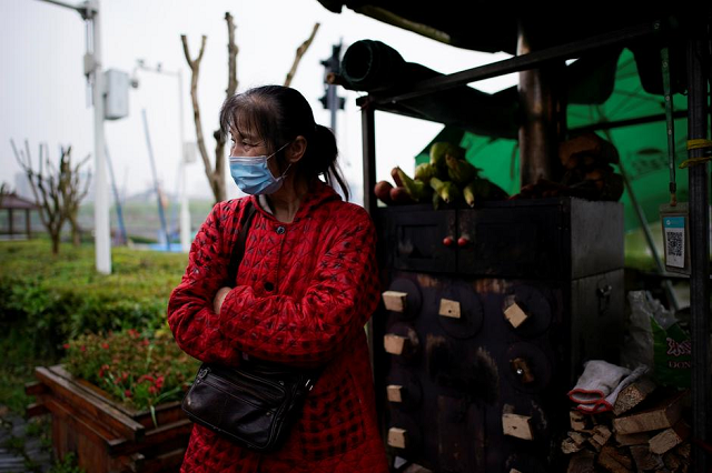li yu 55 a peddler selling corn wears a face mask at an ancient city wall in jingzhou after the tourist attraction reopened as the lockdown was eased in hubei province the epicentre of china 039 s coronavirus disease covid 19 outbreak march 26 2020 photo reuters