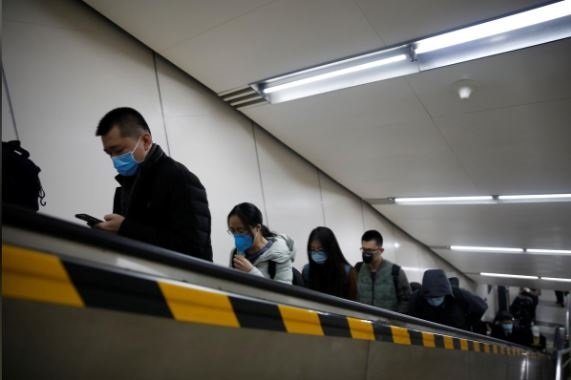 people wearing masks ride an escalator as they exit a subway station photo reuters