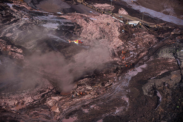 A firefighters' helicopter overflies the area as rescuers work in the search for victims after the collapse of a dam. PHOTO: AFP