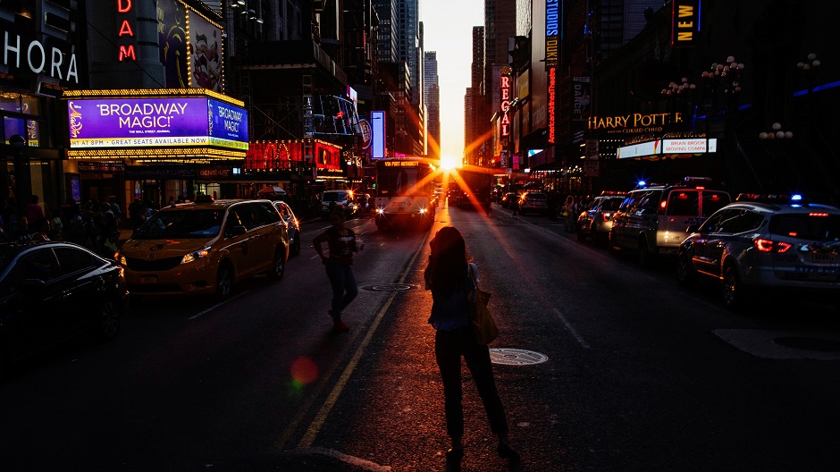  People take pictures of the sun setting over Manhattan aligned exactly with the streets in a phenomenon known as 