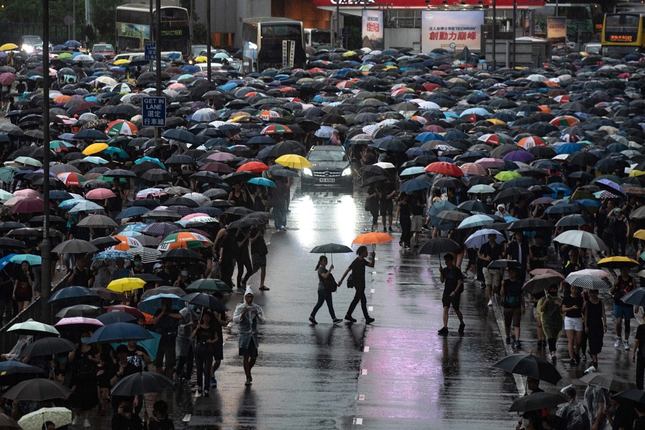 A car drives down a road packed with marching protesters in a rally from Victoria Park in Hong Kong. PHOTO: AFP