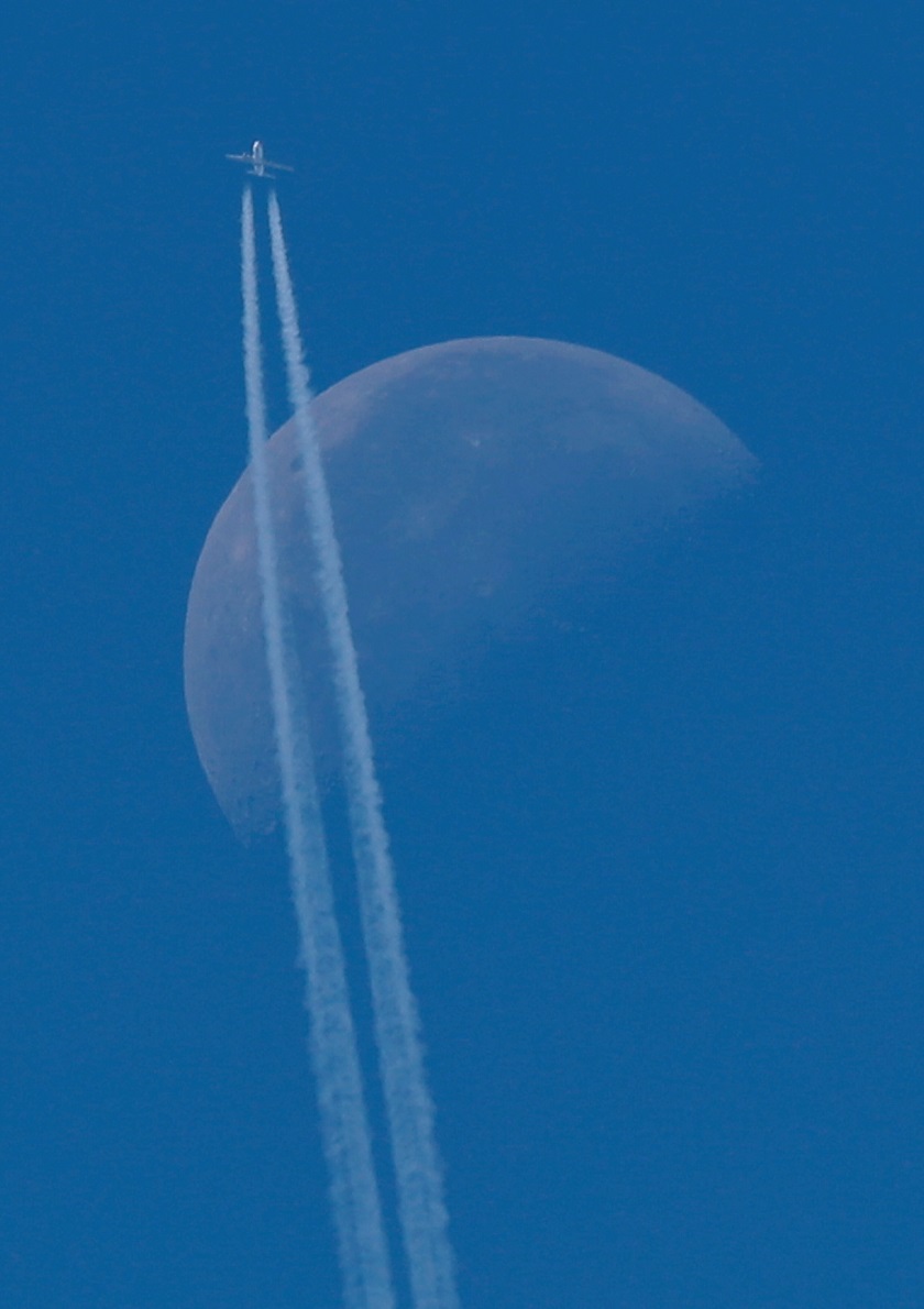 A passenger plane flies in the sky as the Moon is seen in Berlin, Germany. PHOTO: REUTERS