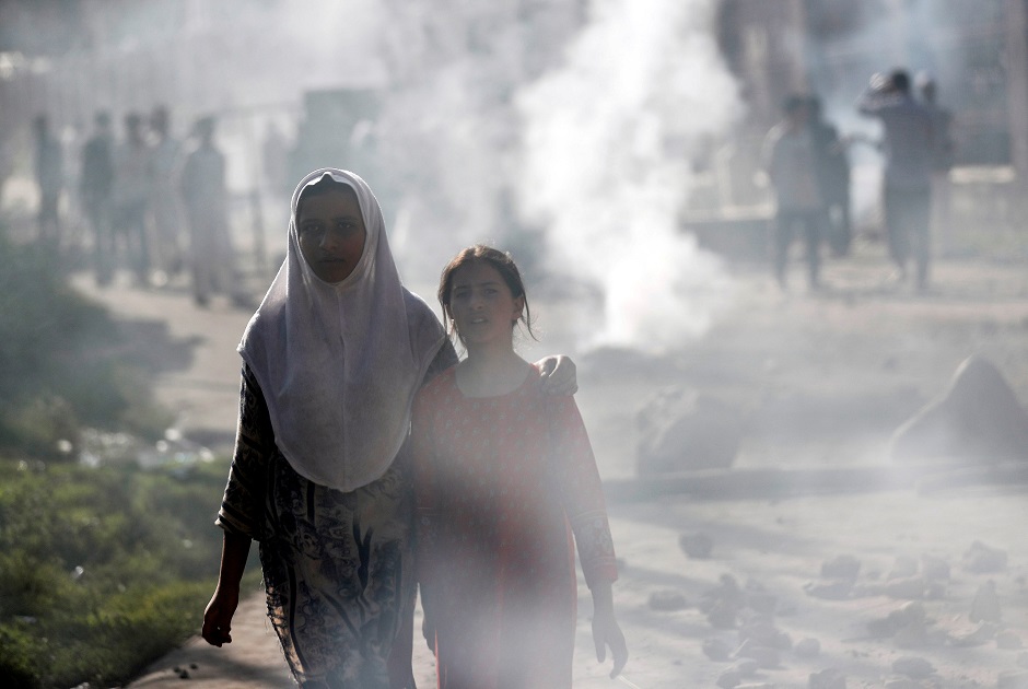 Kashmiri girls walk amidst smoke during clashes between Indian security forces and protestors, after scrapping of the special constitutional status for Kashmir by the Indian government. PHOTO: REUTERS 