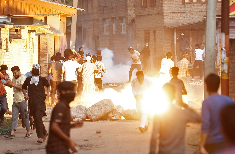 Kashmiris run for cover as a teargas shell fired by Indian security forces explodes during clashes, after scrapping of the special constitutional status for Kashmir by the Indian government, in Srinagar. PHOTO: REUTERS 