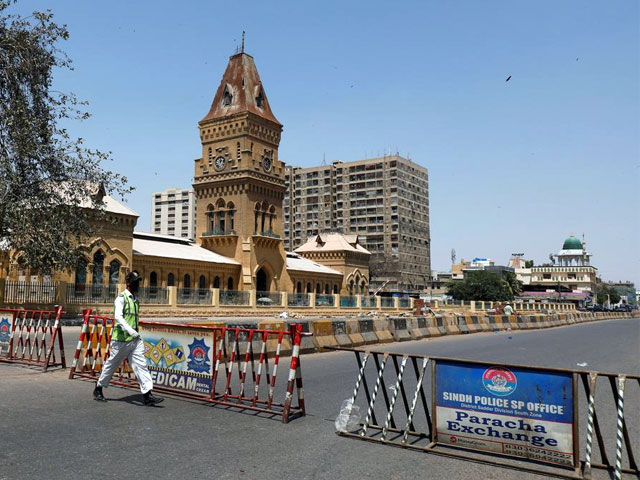 a traffic police officer walks past barriers used to block the road in front of the british era empress market building during a lockdown after pakistan shut all markets public places and discouraged large gatherings amid an outbreak of coronavirus disease photo reuters