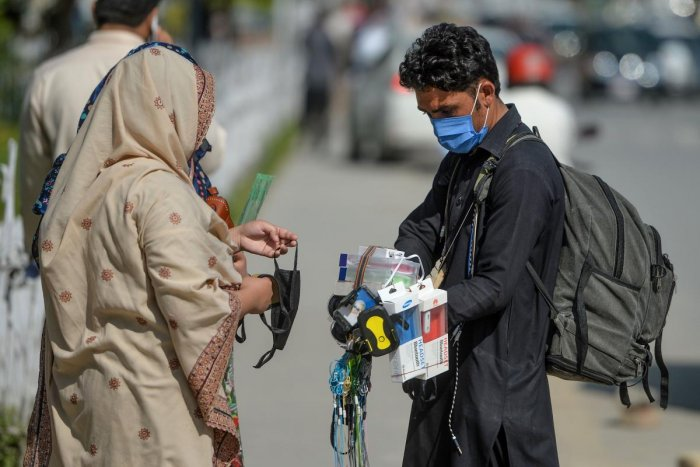 a street vendor wearing a facemask as a preventive measure against the covid 19 interacts with customers alongside a street in islamabad photo afp file