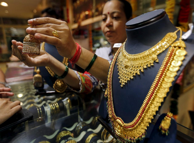 a salesperson shows a gold earring to customers at a jewellery showroom in mumbai india july 21 2015 photo reuters