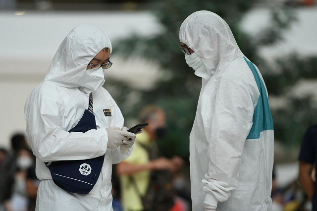 people wear protective suits due to coronavirus disease covid 19 outbreak as they queue at the immigration center in bangkok thailand march 25 2020 photo reuters