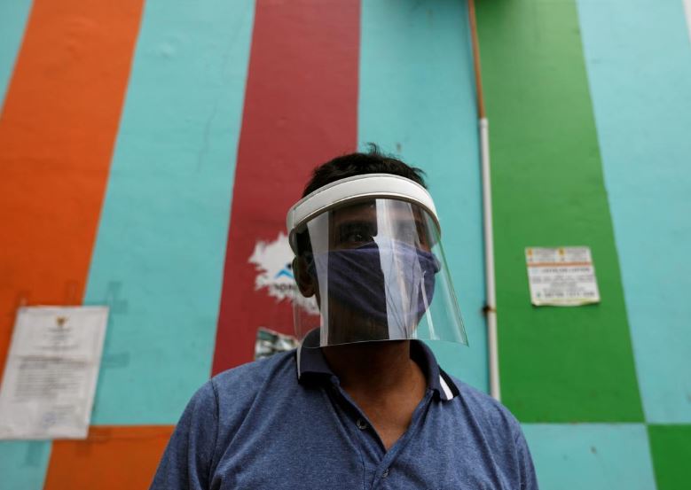 a local wearing a face shield stands guard to check people entering his area as the spread of the coronavirus disease covid 19 continues in jakarta indonesia photo reuters