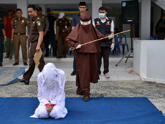 the first female flogger preparing to whip a woman in public in banda aceh after she was caught in close proximity with a man who is not her husband in a hotel photo afp file