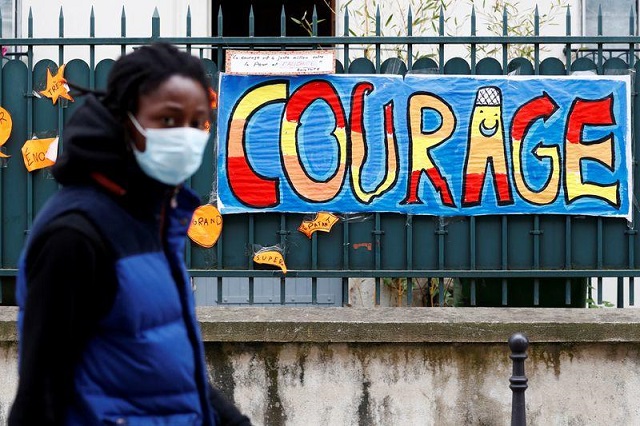 a man wearing a protective mask walks past a sign that reads quot courage quot in paris as a lockdown is imposed to slow the rate of the coronavirus disease covid 19 in france april 25 2020 photo reuters