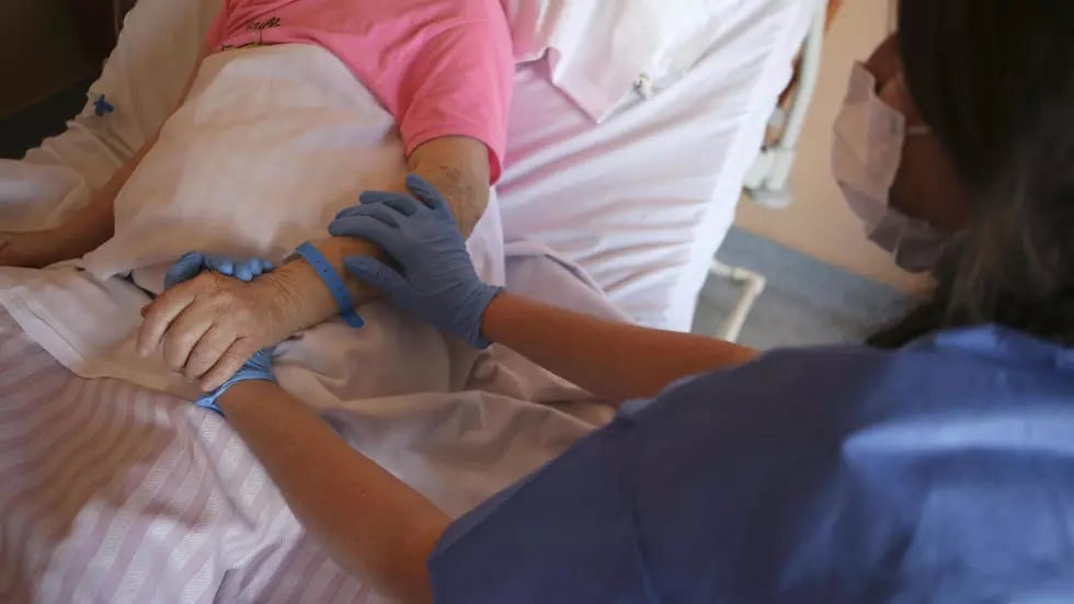 a nurse wearing protective gloves holds the hand of a patient in the palliative care unit of the the eugenie hospital in ajaccio on the french mediterranean island of corsica photo afp