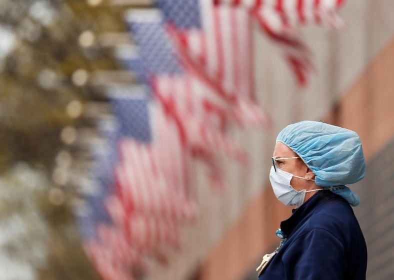 a nurse wearing personal protective equipment watches an ambulance driving away outside of elmhurst hospital during the ongoing outbreak of the coronavirus disease covid 19 in the queens borough of new york photo reuters