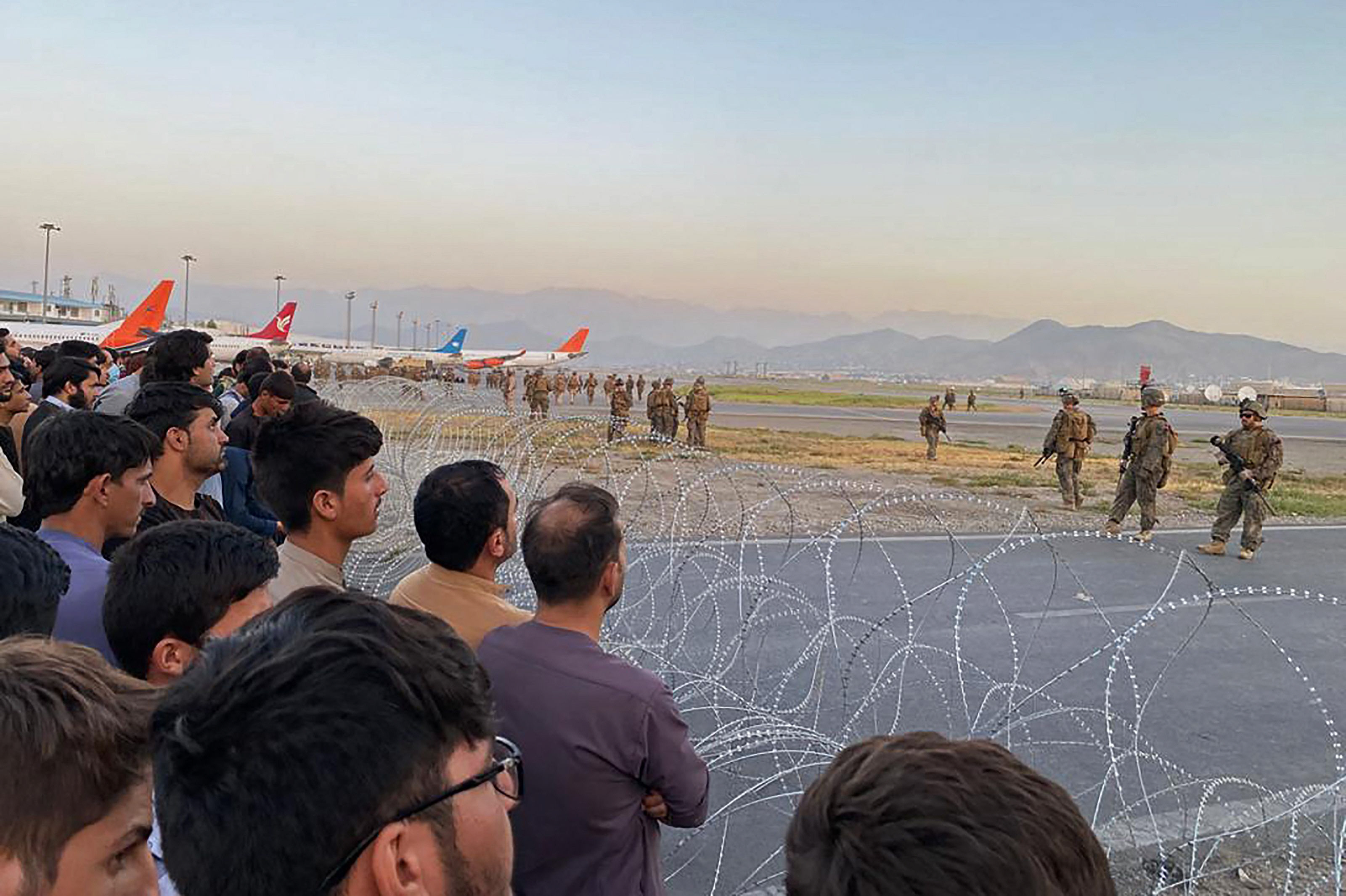 Afghans crowd at the airport as US soldiers stand guard in Kabul. PHOTO: AFP