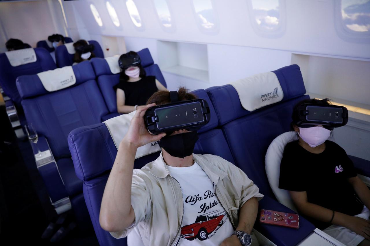 customers in flight seats use virtual reality vr devices at first airlines that provides vr flight experiences including 360 degree tours of cities and meals amid the covid 19 pandemic in tokyo japan august 12 2020 photo reuters