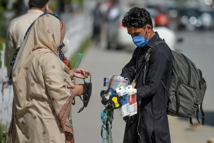 a street vendor wearing a facemask as a preventive measure against the covid 19 interacts with customers alongside a street in islamabad photo afp file a street vendor wearing a facemask as a preventive measure against the covid 19 interacts with customers alongside a street in islamabad photo afp file