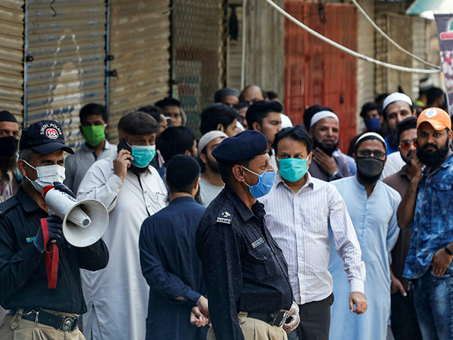 a police officer uses a megaphone to disperse shopkeepers gathered to reopen their shops at a closed market in karachi photo reuters file