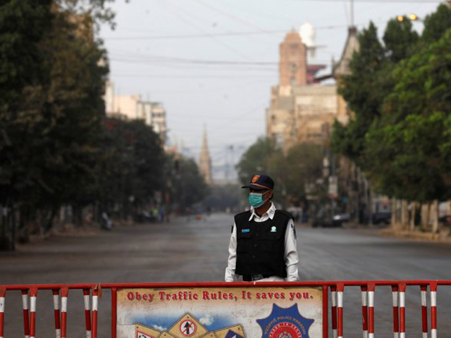 a traffic police officer stands with a barrier on a deserted road of a business district during a partial lockdown in karachi photo reuters file