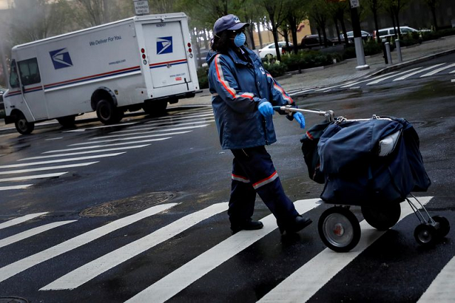 a united states postal service usps worker works in the rain in manhattan during the outbreak of the coronavirus disease covid 19 in new york city new york us april 13 2020 photo reuters