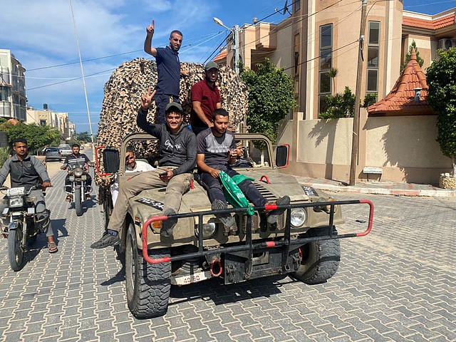 Palestinians celebrate as they ride on an Israeli military vehicle that was seized by Palestinian gunmen who infiltrated areas of southern Israel, in the southern Gaza Strip October 7, 2023. REUTERS