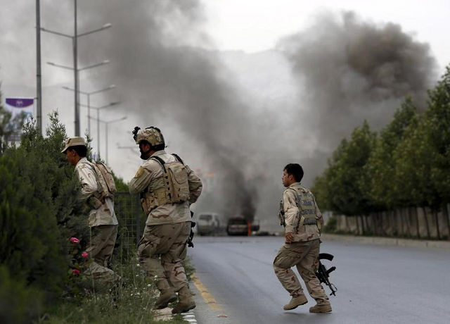 members of afghan security forces cross a road as smoke billows from the site of an attack near the afghan parliament in kabul photo reuters