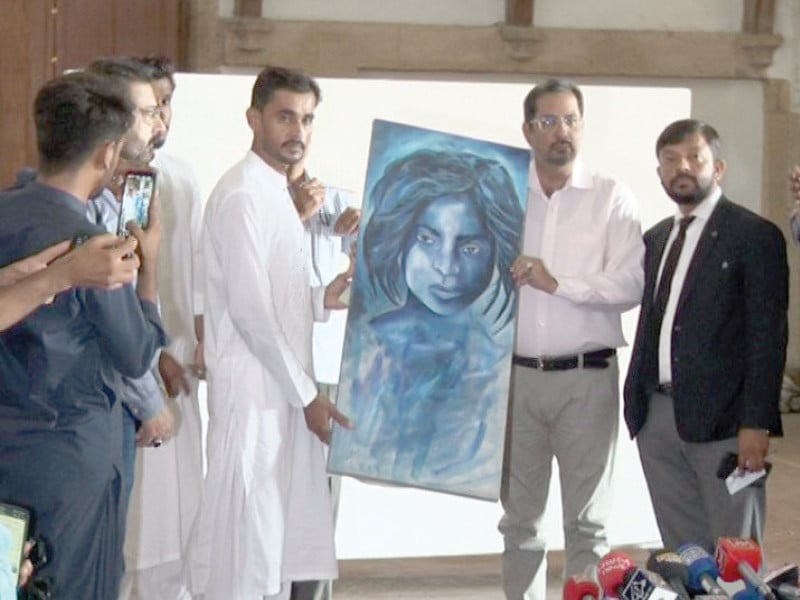 artist saifi soomro left receives his painting from the kmc culture and sports director right at a ceremony at frere hall on monday photo express