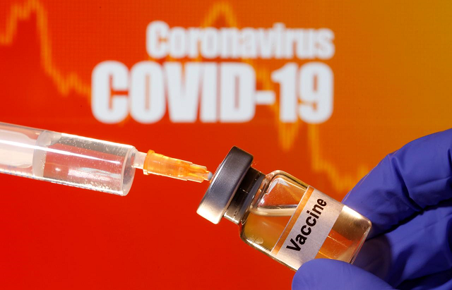 a small bottle labeled with a quot vaccine quot sticker is held near a medical syringe in front of displayed quot coronavirus covid 19 quot words in this illustration taken april 10 2020 photo reuters