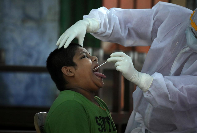 a medic wearing protective gear takes a swab from a boy to test for the coronavirus disease covid 19 during an extended lockdown to slow the spreading of the disease in a residential area in kolkata india may 11 2020 photo reuters